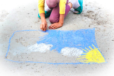 image of child drawing with chalk on the ground