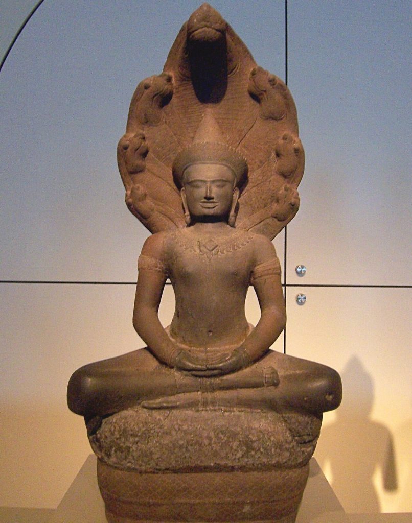 stone statue of a meditating buddha with Naga in the background