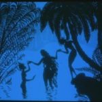 Blue silhouette of three people holding hands in tropical water scene