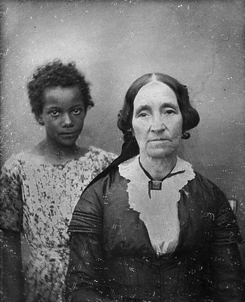 old black and white photo of a old woman with young black girl in the background