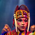 The Festival of the Lion King is a live stage show featuring acrobatics and musical performances inspired by The Lion King. One actress dresses up with tusks.