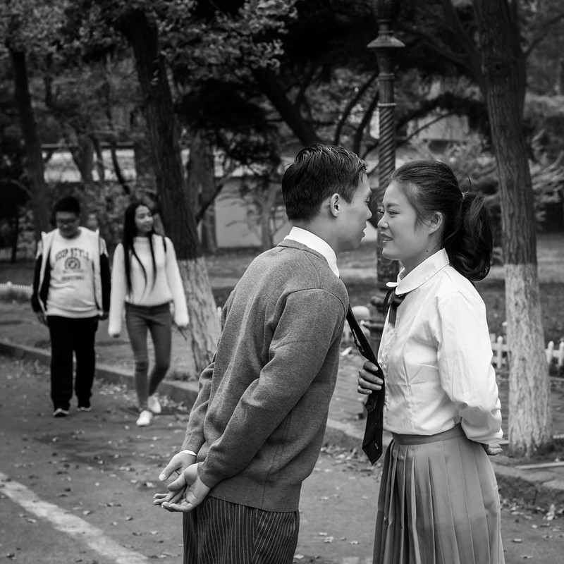 Black and white of of a teenage school boy and a girl about to kiss