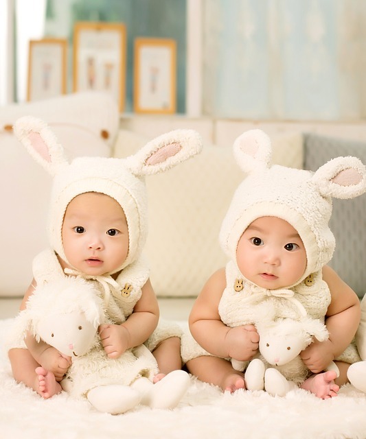 Photo of identical twins dressed with bunny ears holding stuff animals