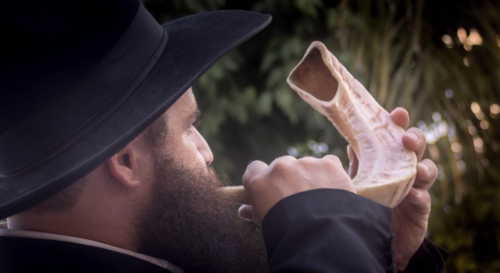 Photo of a man blowing the shofar.