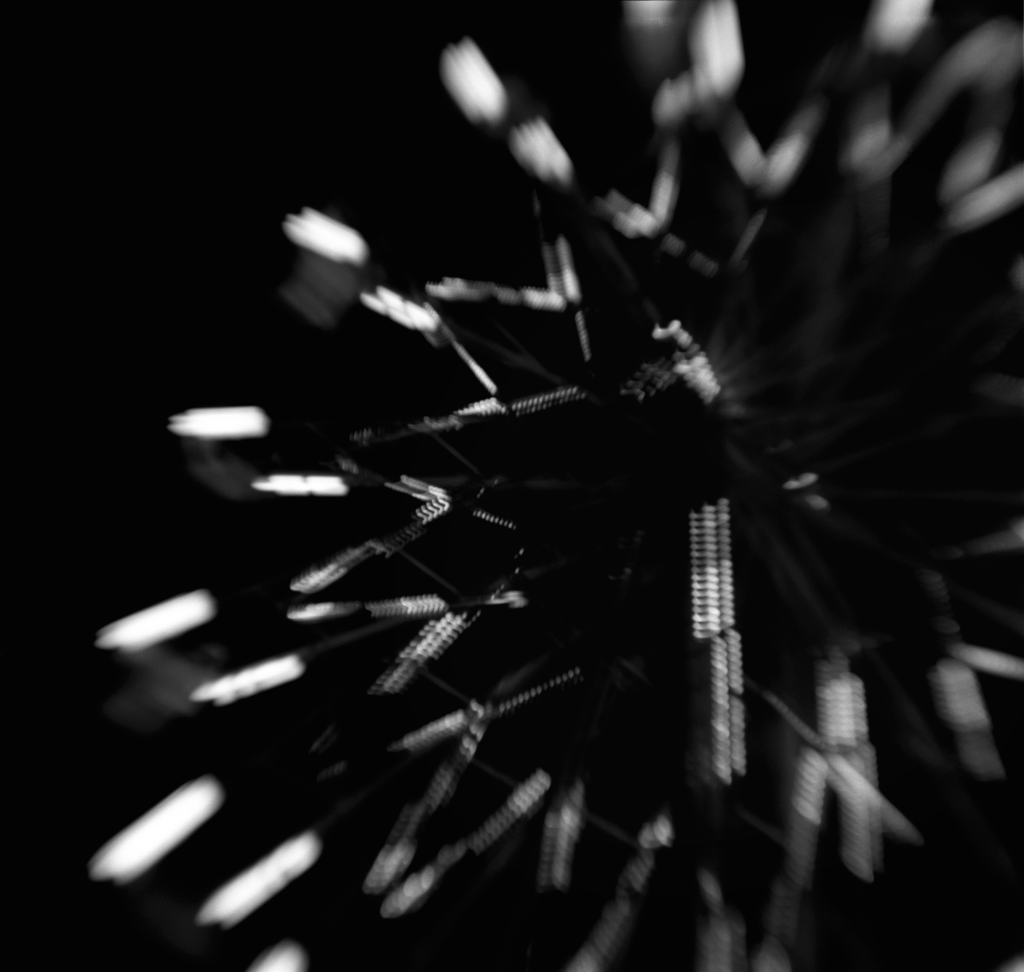 Black and white photo of the out of focus lights on a ferris wheel at night.