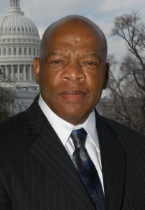 Photo of a Black man in a suit and tie posing in front of the Capitol building