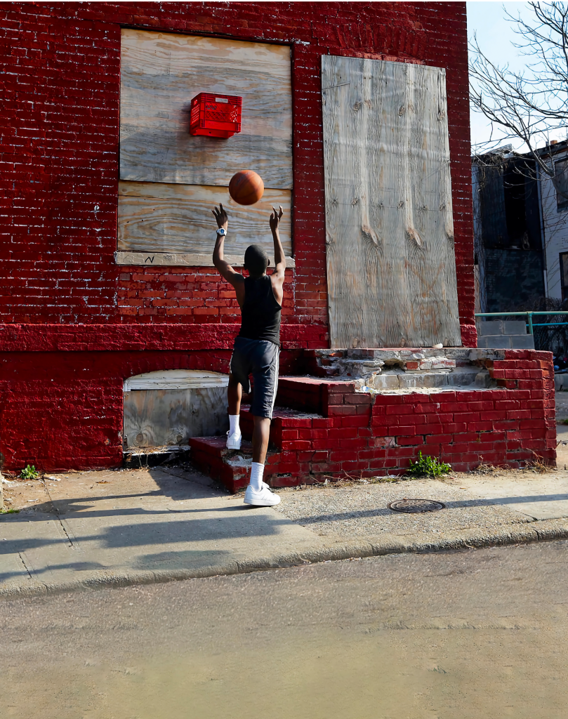 image of boy shooting a basketball into a homemade milk cart hoop.