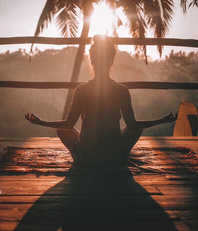 photo of a woman in a meditation pose with a sunset in the background