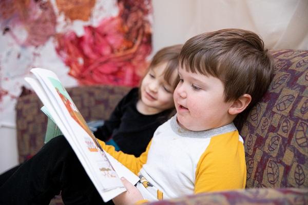 Two children read a book together.