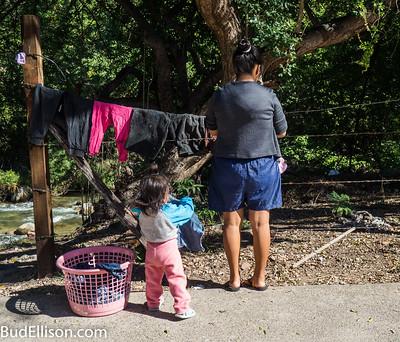 A mother and a toddler hang laundry on a drying line.