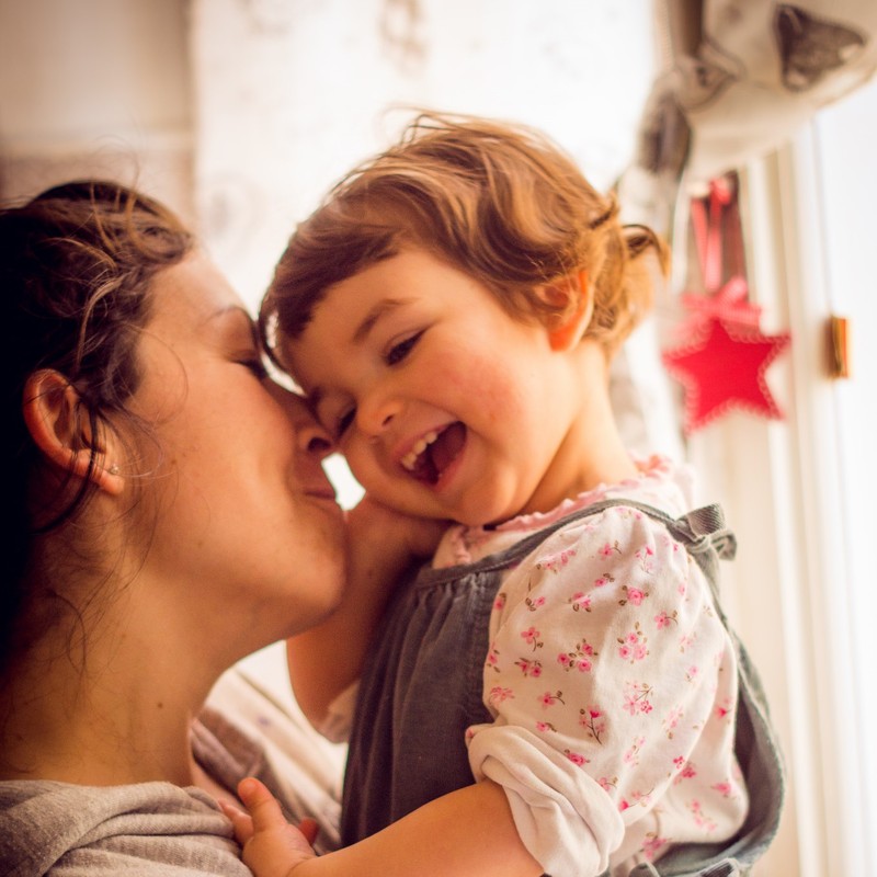 A mother cuddles with her daughter.