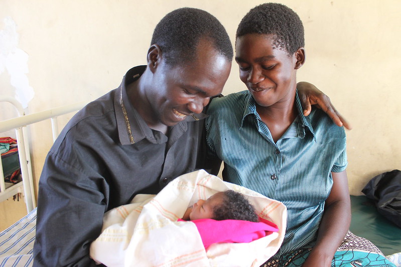 Photo of father holding baby next to mother.