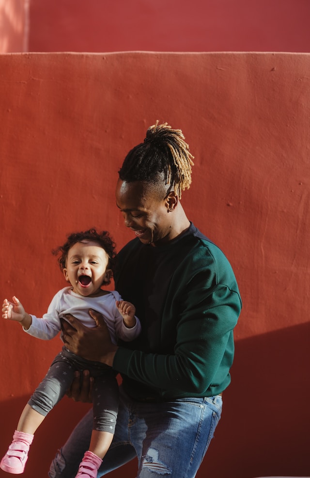 Image of African American father holding his happy toddler son