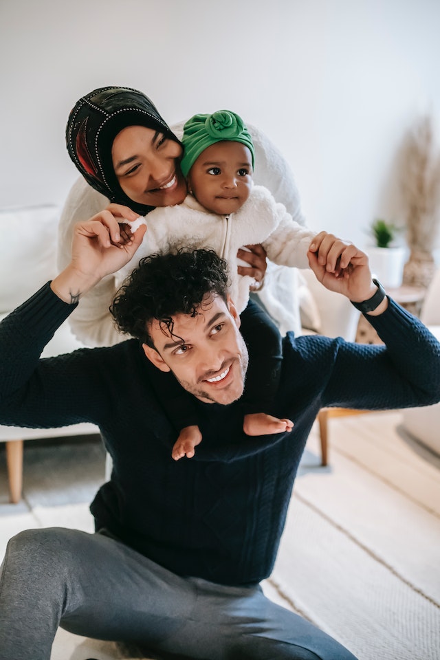 Image of mother embracing baby sitting on father