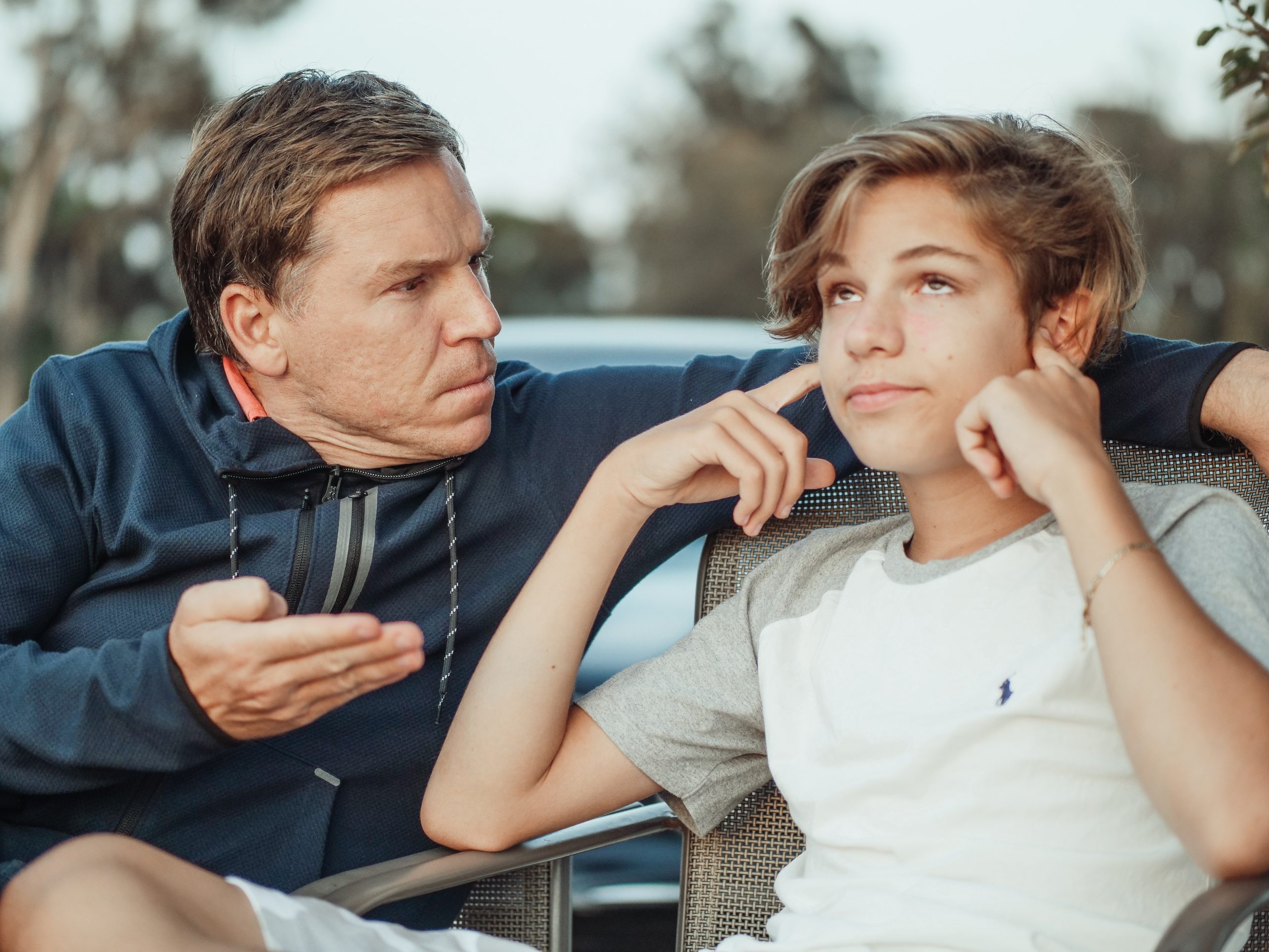 Image of father and teenage son covering his ears