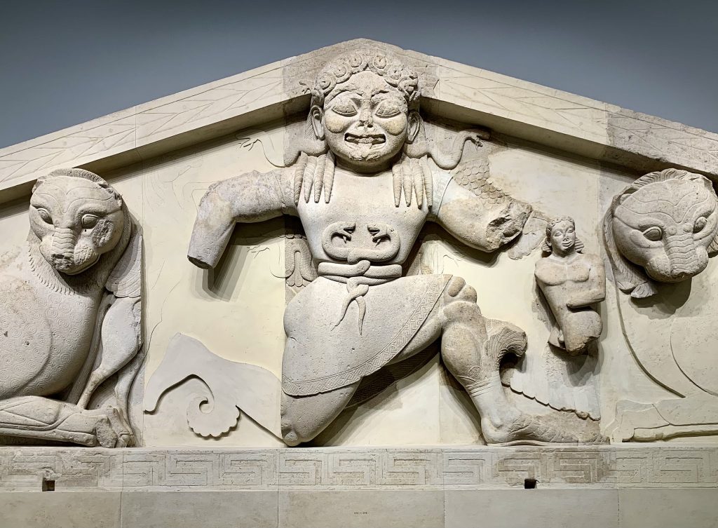 stone relief of a gorgon wearing a belt of intertwined snakes