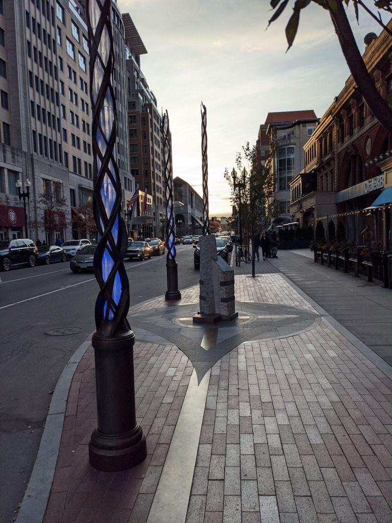 Photo of a city street with three columns in the sidewalk