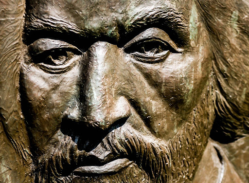 Photo of a close up of a carved face of a male-presenting individual with a beard