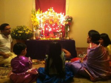 Photo of a Hindu family sitting around the alter with candles.