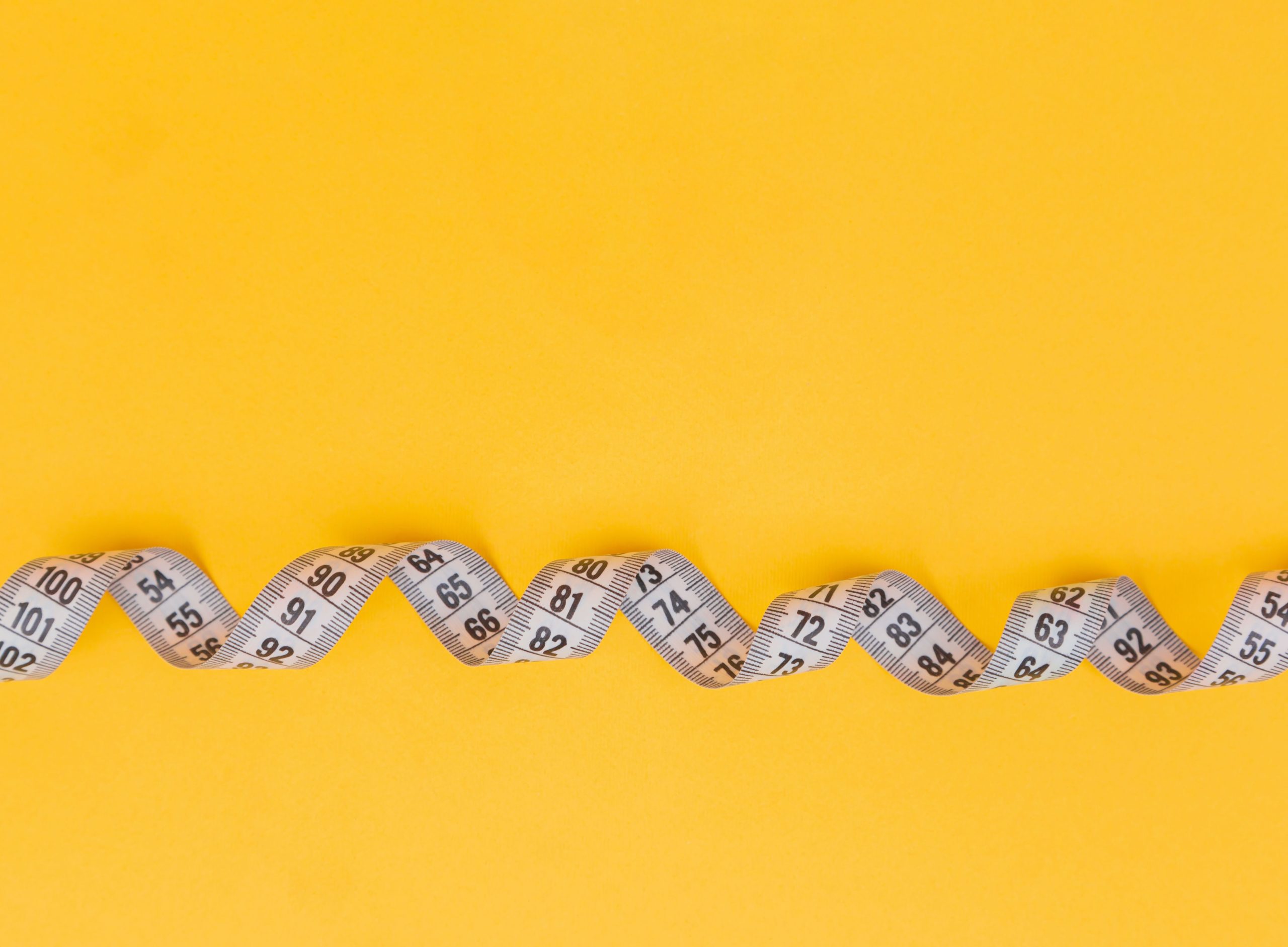 Image of curling measuring tape against yellow background