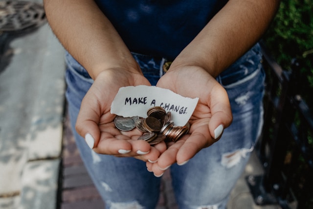 Hands holding coins and a note that says “make a change.”